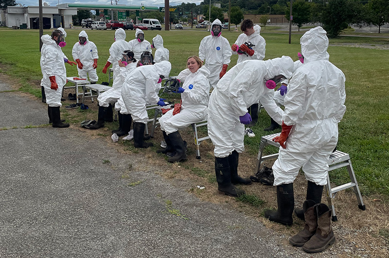 A class dresses out in hazmat suits for an outdoor hazardous materials training.