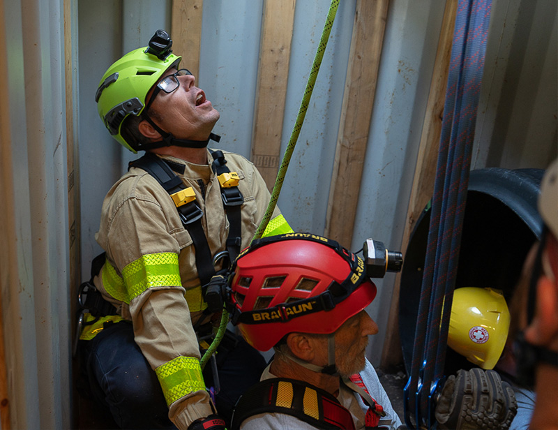 Two first responders participate in confined space rescue training in a confined space simulator.