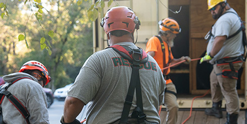 Several first responders hold ropes in a confined space rescue training.