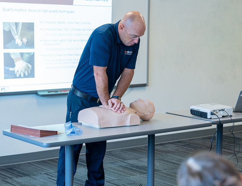 A man does chest compressions on a mannequin during CPR training.