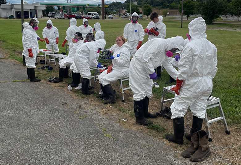 A class dresses out in hazmat suits for an outdoor hazardous materials training.