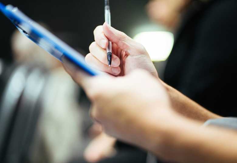 Person writing on clipboard